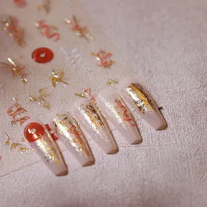 Détail macro de stickers ongles bambou doré et nuage rouge sur faux ongles mats