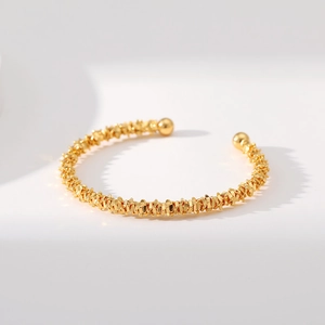 Detalle de brazalete de latón chapado en oro de 18K con acabado texturizado y esferas