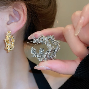 Close-up of sparkling star-shaped crystal hoop earrings in gold and silver finish