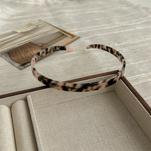 Close-up of a leopard print acetate headband resting on a linen jewelry tray display
