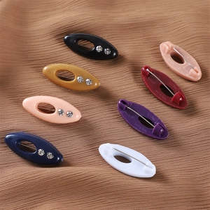Oval rhinestone safety pins for hijabs and scarves in assorted colors shown on ribbed fabric