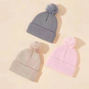 Dettagli della maglia di berretti per bambini in grigio, beige e rosa con grandi pompon