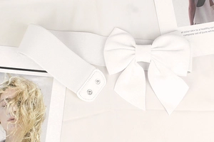 Detail of white elastic waist belt with large bow knot accessory on fashion magazine background