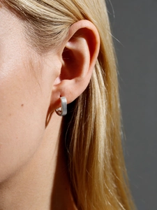 Close-up of a brushed silver square earring hoop worn on a woman for a minimalist look