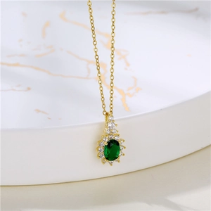 Detail shot of a sunburst gold necklace featuring an oval green crystal and zircon halo