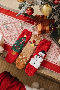 Detail of soft coral fleece Christmas socks featuring reindeer, snowman and tree patterns