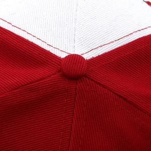 Macro shot of cotton twill panels and top button stitching on the red baseball cap