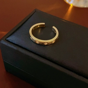 Détail macro de la bague dorée gravée d'étoiles avec zircon sur cuir noir
