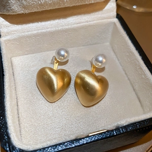 Macro view of matte gold heart earrings with brushed metal texture and pearl details