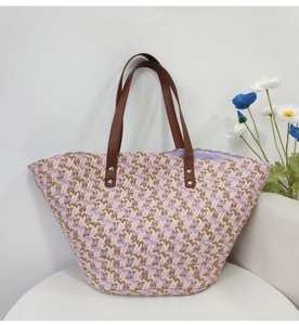 Close-up of colorful straw woven tote bag featuring deep brown leather shoulder straps
