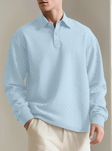 Detailed close-up of light blue textured jacquard knit fabric on a long sleeve polo shirt