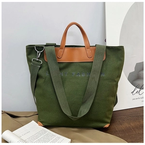 Detail of dark green canvas tote bag with brown leather handles and LIGHT FASHION text