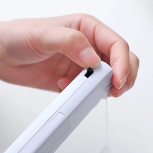 Portable white reading lamp with hand flipping a black switch on a solid background