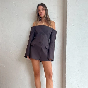 Detail of a brown off-the-shoulder blazer dress with buttons and long sleeves on a model