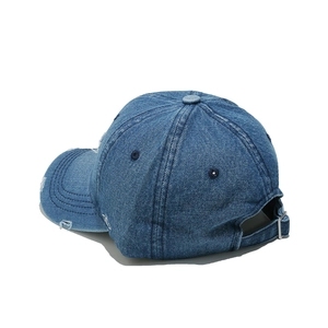 Close-up of distressed denim baseball cap with metal buckle and torn fabric detail