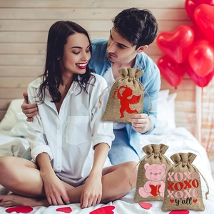 Linen Valentine's Day gift bags with heart prints and drawstrings held by a couple
