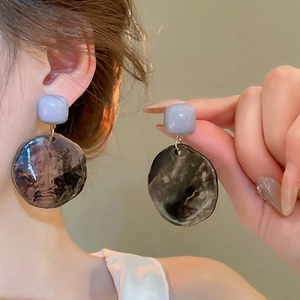 Detail of irregular resin drop earrings with lavender studs and smoky ink textures