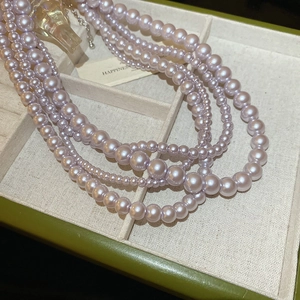 Detail of multi-layer purple pearl necklace with silver lobster clasp in a jewelry box