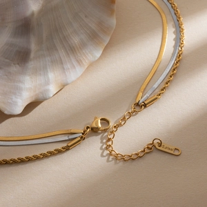 Detail of layered S.Steel gold and silver snake chain necklace with lobster clasp and tag