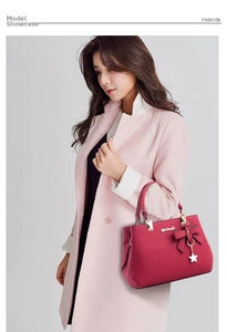 Detail of dark pink leather handbag with 3D bow decoration and gold star pendant