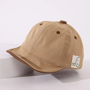 Detail of baby cotton cap with Good Luck label and soft brim on a white pedestal