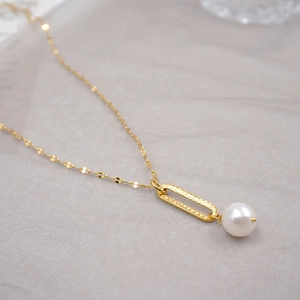 Minimalist gold lip-chain necklace featuring a hammered metal ring and glossy white pearl