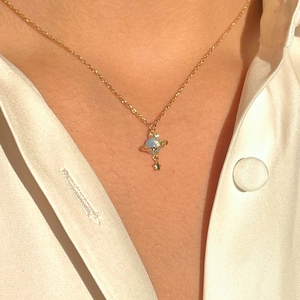 Elegant gold planet pendant necklace with blue orb and star worn on model neck