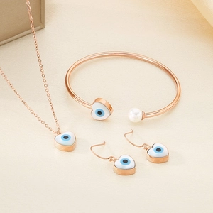 Macro shot of rose gold jewelry set featuring heart evil eye charms and a pearl accent
