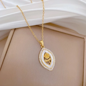 Vue macro d'un pendentif rose dorée avec émail blanc et zircons sur tissu en soie