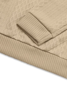 Detailed macro view showing the khaki jacquard knit texture and ribbed cuffs of the sweater