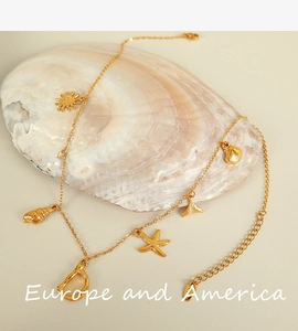 Detail of 18K gold-plated necklace with starfish, shell, pearl and letter D charms