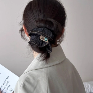 Dark wash denim scrunchie with yellow stitching and vintage label for stylish hairstyles
