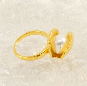 Detailed close-up of a golden shell ring featuring a large white pearl center
