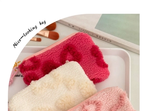 Detailed plush cosmetic bags in pink and cream with 3D heart embroidery and soft texture