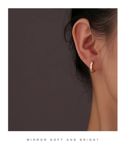 Gros plan d'un modèle portant une boucle d'oreille créole en or ornée de zircons