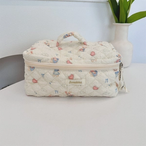 Detail of a quilted cotton makeup bag with bear and heart prints and top handle
