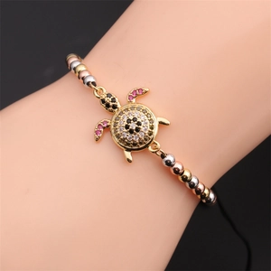 Close-up of zircon turtle bracelet on woman wrist with three-tone metal beads