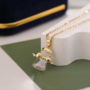 Élégant collier doré avec pendentif aile d'ange et cristal sur un présentoir blanc