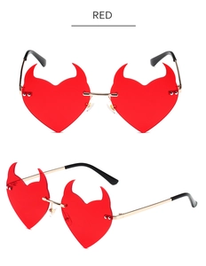 Detail of red heart-shaped devil horn sunglasses with slim gold metal temples and frames