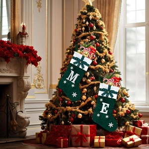 Close-up of green knitted Christmas stockings with white letter embroidery and snowflakes