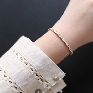 Close-up of gold tennis bracelet with rectangular crystals on a lace sleeve