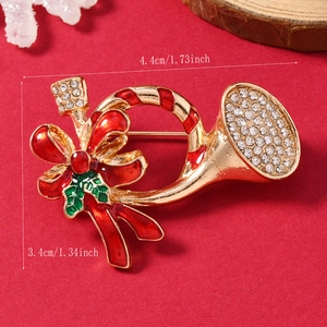 Macro view of Christmas horn brooch with red enamel and rhinestones on festive background
