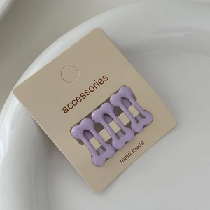 Three-piece set of purple bone-shaped mini hair clips on card with accessories text