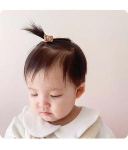 Close-up of a cute brown bear hair tie on a baby's ponytail with a soft matte finish
