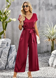 Outdoor lifestyle shot of a burgundy short sleeve wide leg jumpsuit with waist belt detail