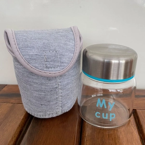 Mini high borosilicate glass jar with metal lid and gray sleeve on a wooden table