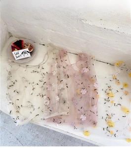 Detail of embroidered mesh fabric layers on floral handbags in beige and pink colors