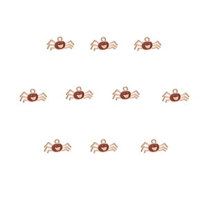 Detail view of ten rose gold alloy charms with brown enamel crab-like smiling face designs