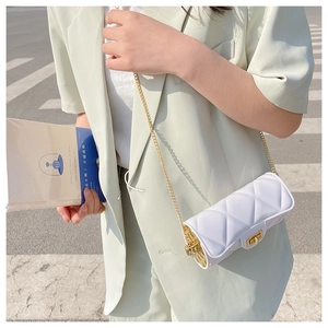 Close-up of white quilted mini cylinder bag with gold chain and twist lock on green blazer