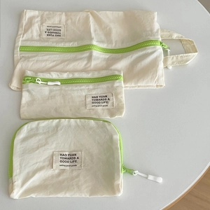 Set de tres bolsas de viaje en color blanco roto con cremalleras verde neón brillante